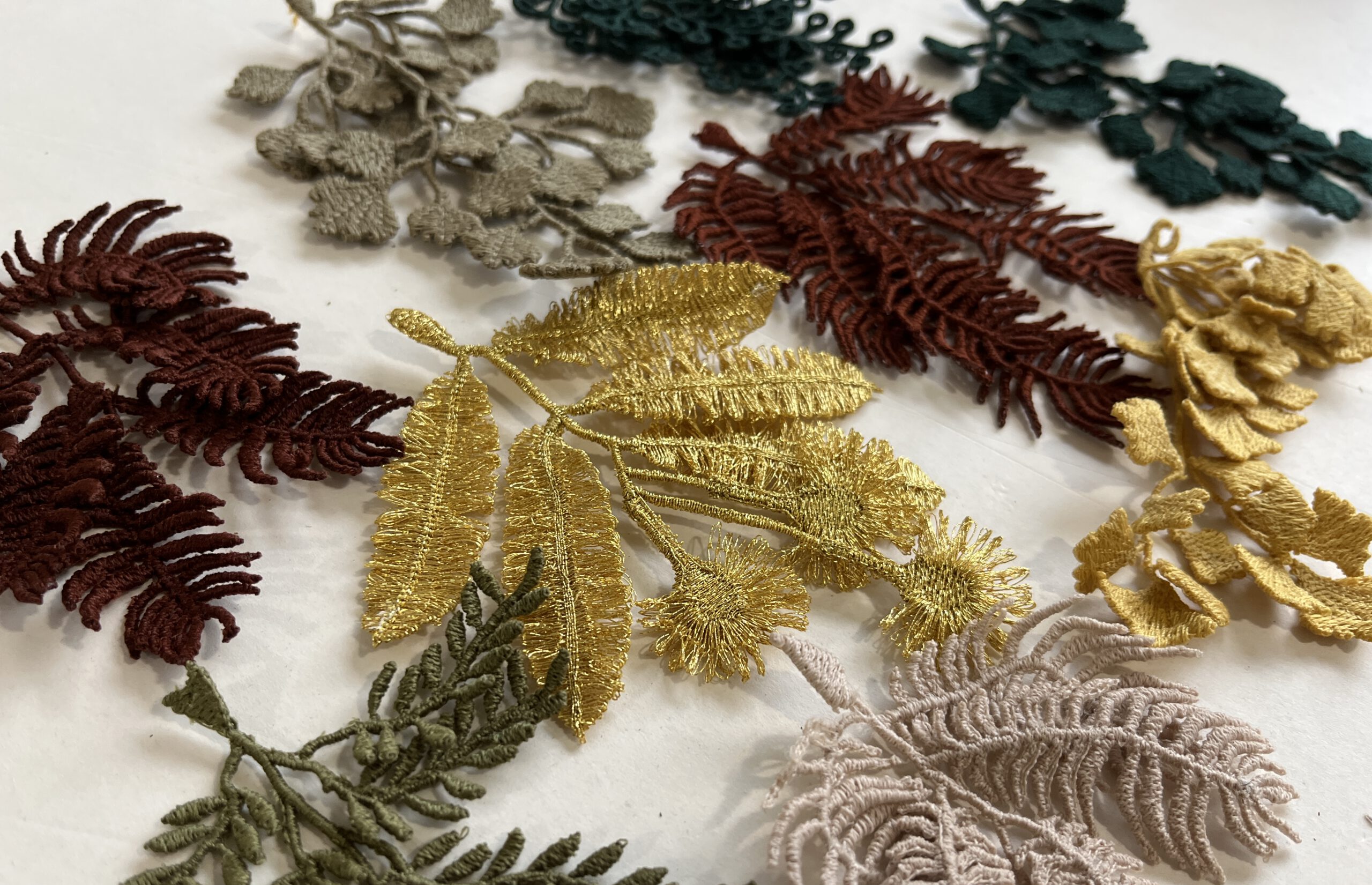 Embroidered brooches in autumn colors and in different nature inspired shapes laying on a table